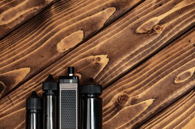 Vape and vape juice bottles on dark brown wooden background